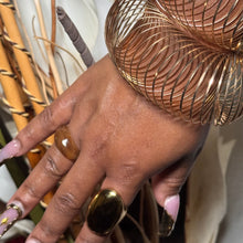 Load image into Gallery viewer, Hand with gold ring and bracelet against a blurred natural background

