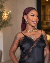Load image into Gallery viewer, A woman with dark red braided hair wearing a black satin camisole top with lace cups, styled with a gold chain necklace and hoop earrings, posing in an indoor setting.
